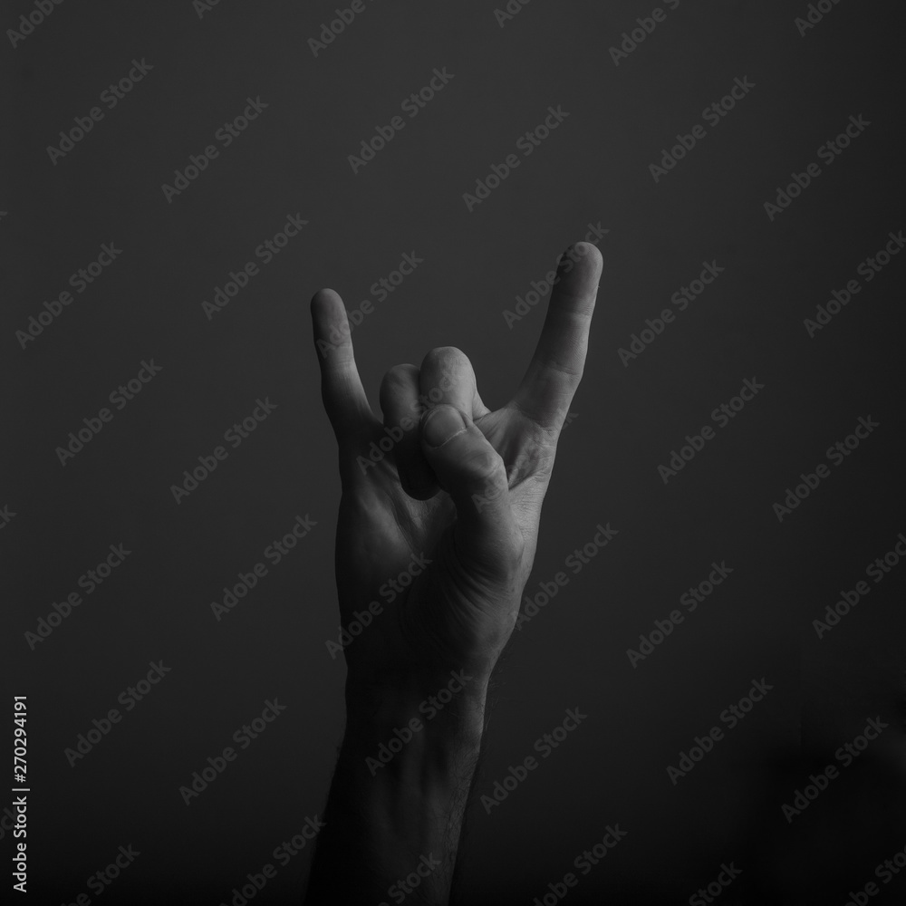 male devil horn rock and roll hand gesture against dark background male devil horn rock and roll hand gesture against dark background
