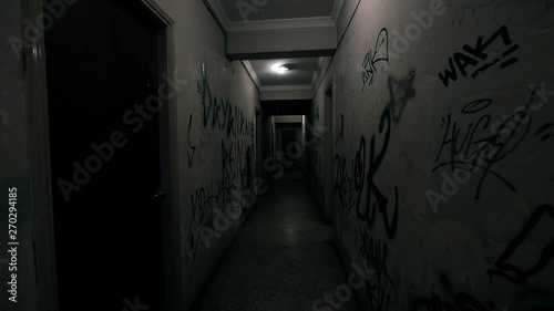 Old Apartment,Ghetto Building,long Dark Hallway.Tracking inside a dark long hallway of a ghetto apartment complex.Graffiti vandalism and abandonment in a poverty stricken neighbourhood. photo