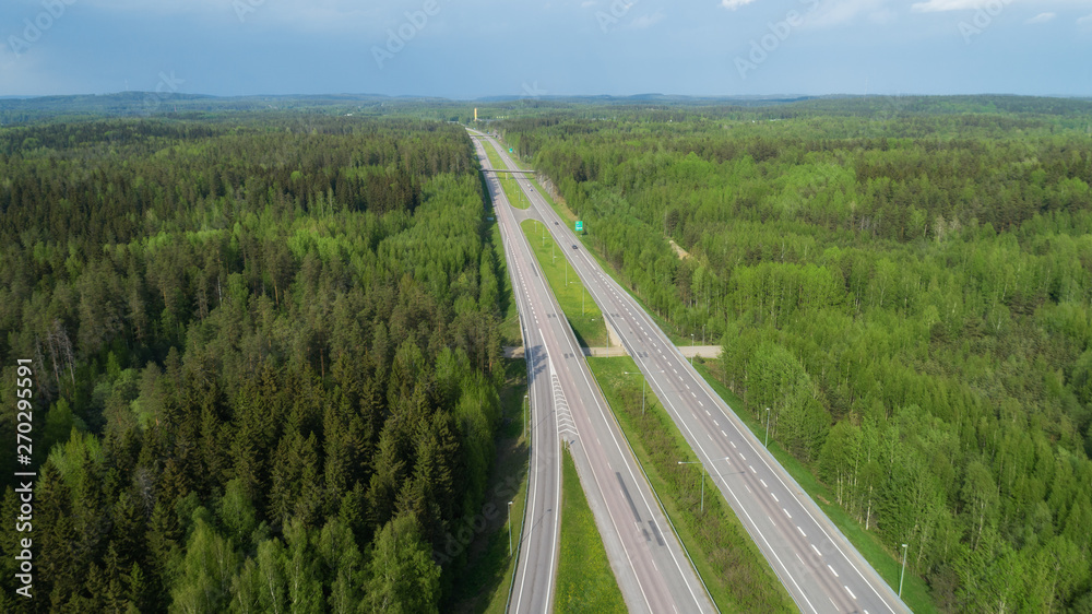 Straight highway through deep forest aerial view. Bright summer image. FInland