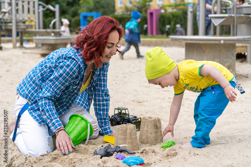 a little boy shows a young grandmother how to make sand figures. Play in the sandbox on the playground.