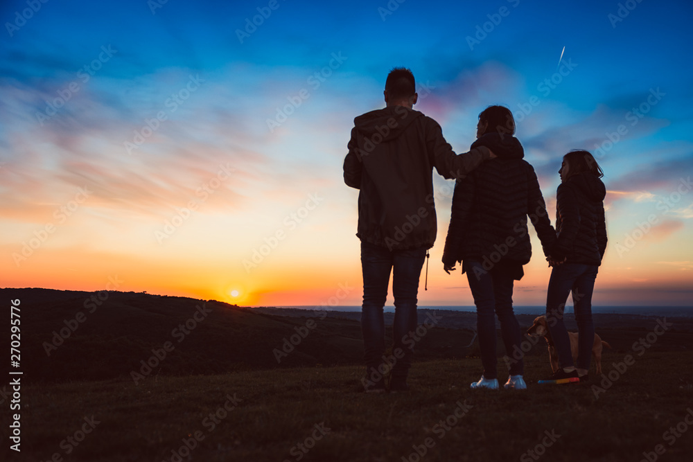Family with dog embracing while standing on the hill