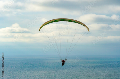Man doing sport (Para-glider). Man paragliding in the clouded sky. Paragliding is an extreme sport and recreation. Torrey Pines Gliderport. San Diego. California, USA.