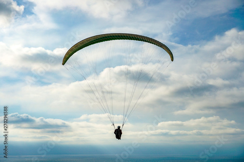 Man doing sport (Para-glider). Man paragliding in the clouded sky. Paragliding is an extreme sport and recreation. Torrey Pines Gliderport. San Diego. California, USA. photo