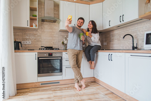 cheerful man with woman taking selfie on the kitchen while drinking tea © phpetrunina14