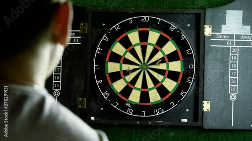 Man throwing a dart arrow in target center of dartboard in game of darts. 4K