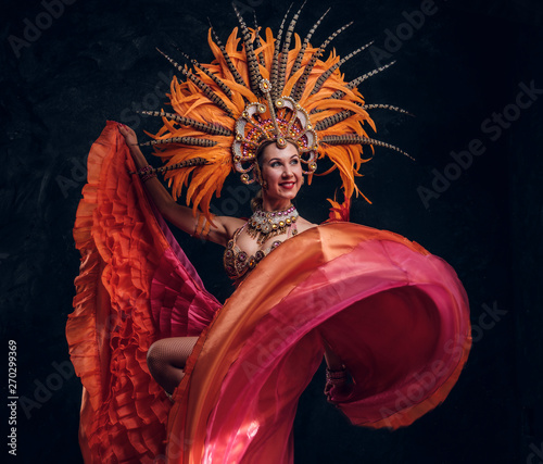 Attractive young female dancer in special feather costume is dacing at studio. photo