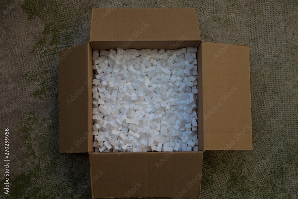 cardboard box with packing foam pellets white polystyrene foam, styrofoam  popcorn or packing noodles used to cushion the contents of packages while  shipping commonly made of expanded polystyrene foam Stock Photo