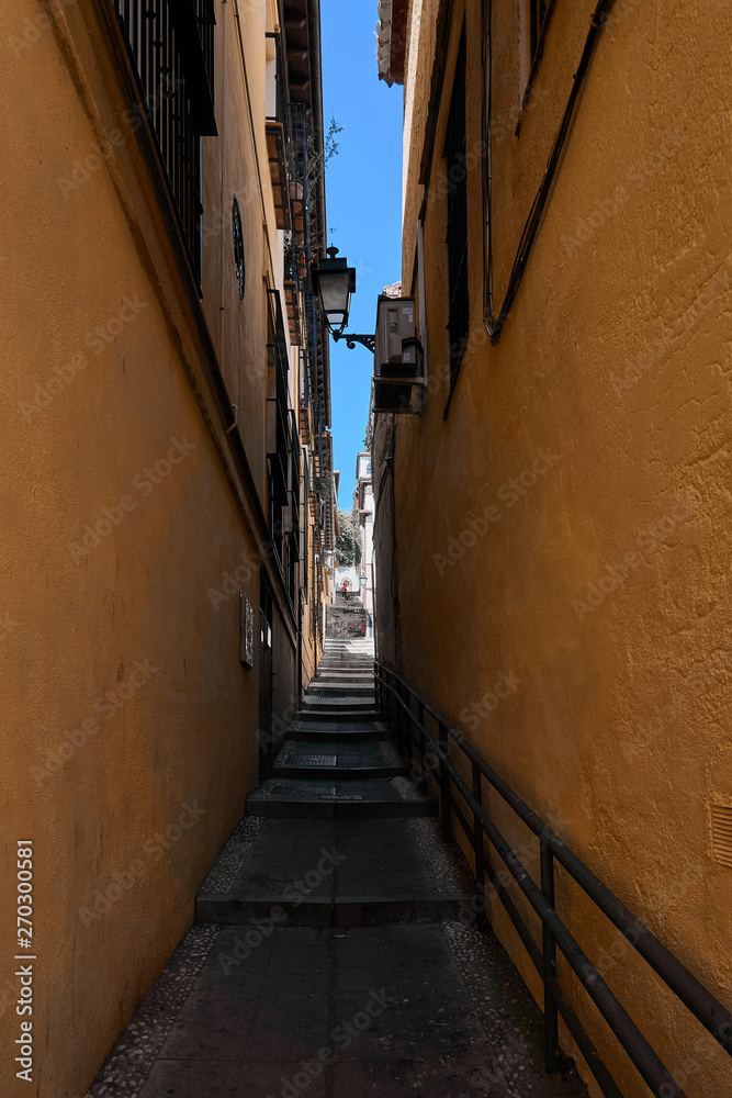 dark stepped ascending path within colorful and narrow alley
