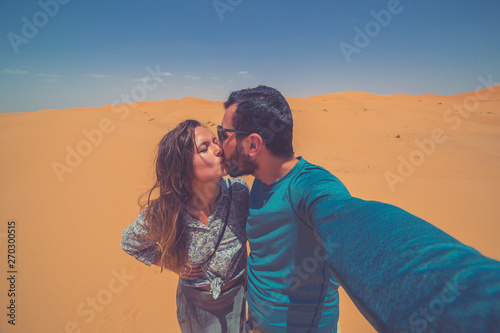 Happy tourist smiling take photo selfie in the Middle of the red Sahara desert with giant red dunes in background. Merzouga, Morocco, Africa