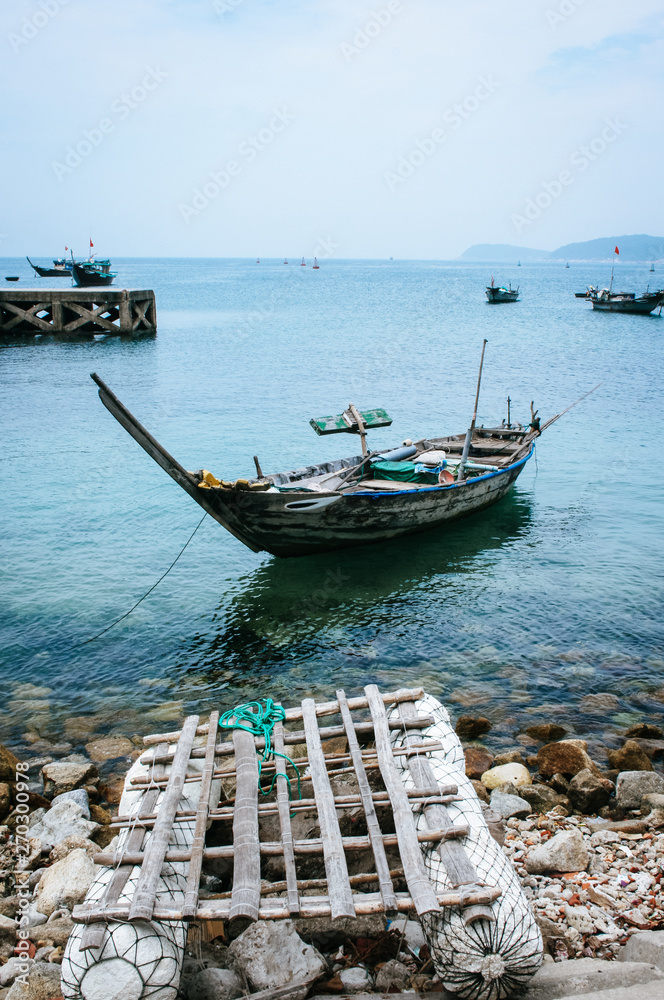 Traditional Vietnamese fishing boat and hand made raft at anchor