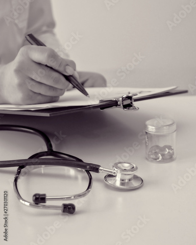Medical content. Doctor writes a prescription of medicine. Physician. Healthcare. Treatment. Paperwork. Black & White Photography. Background. Copy space for your text.