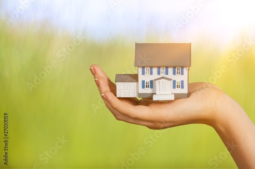 Building, mortgage, real estate and property concept - close up of hand holding house model