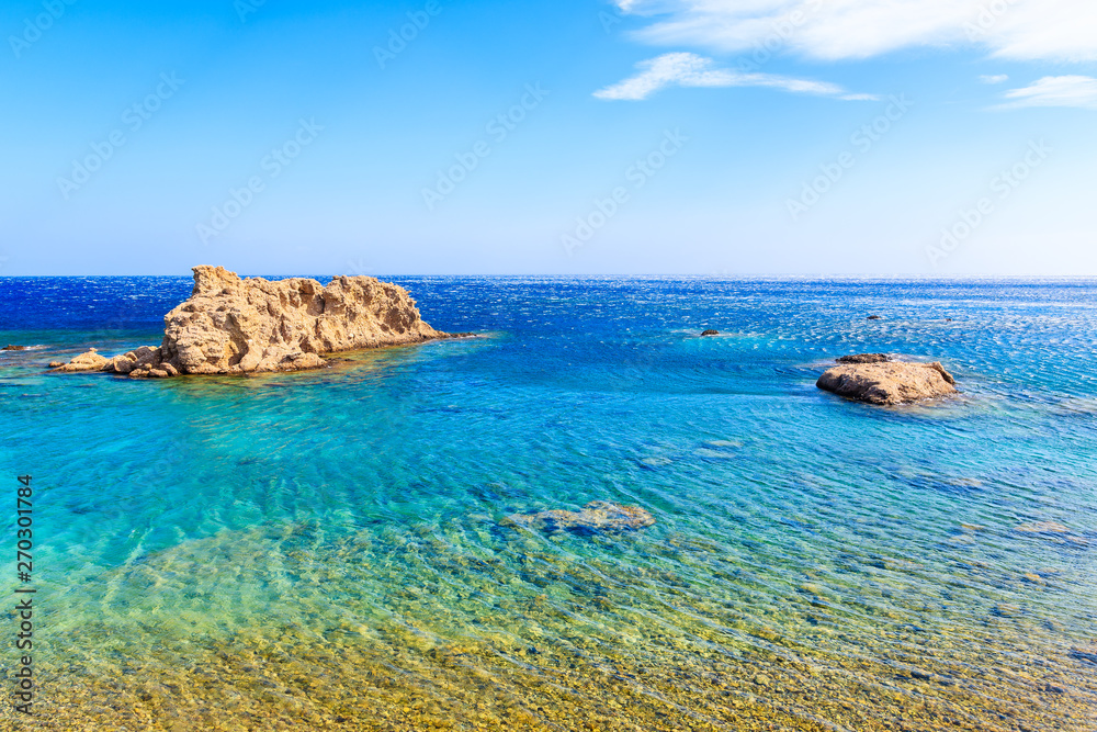 Rocks in crystal clear azure sea near beach on Karpathos island near Ammopi village, Greece
