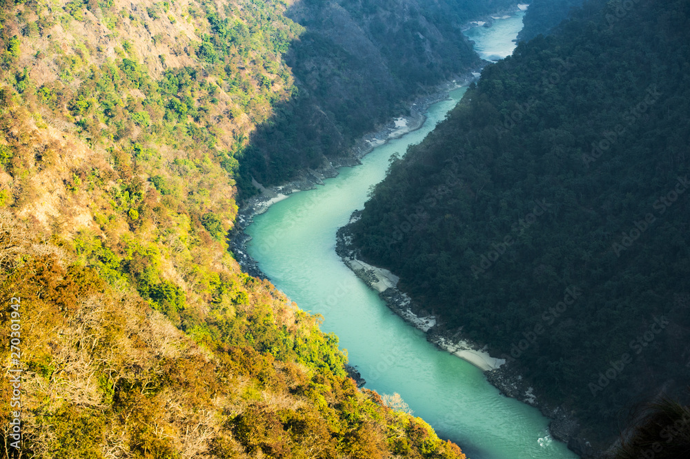 Stunning view of some green mountain peaks with the Sacred Ganges River flowing between them in Rishikesh, India.
