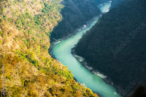 Obraz na płótnie Stunning view of some green mountain peaks with the Sacred Ganges River flowing between them in Rishikesh, India. w salonie