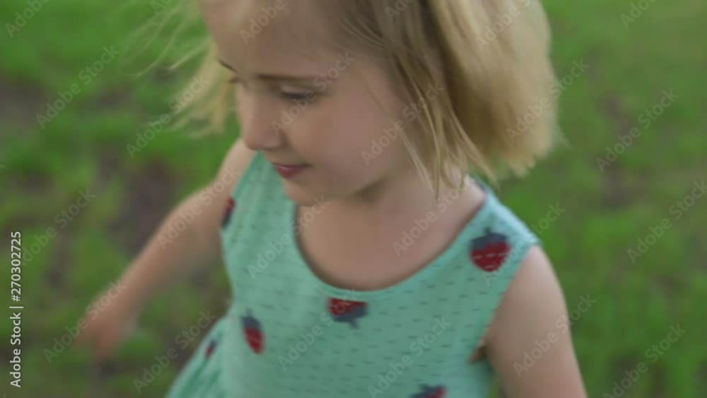 Young blonde hippie mother having quality time with her baby girls at a park blowing dandelion - Daughters wear similar dresses with strawberry print - Family values Young blonde hippie mother having quality time with her baby girls at a park blowing dandelion - Daughters wear similar dresses with strawberry print - Family values