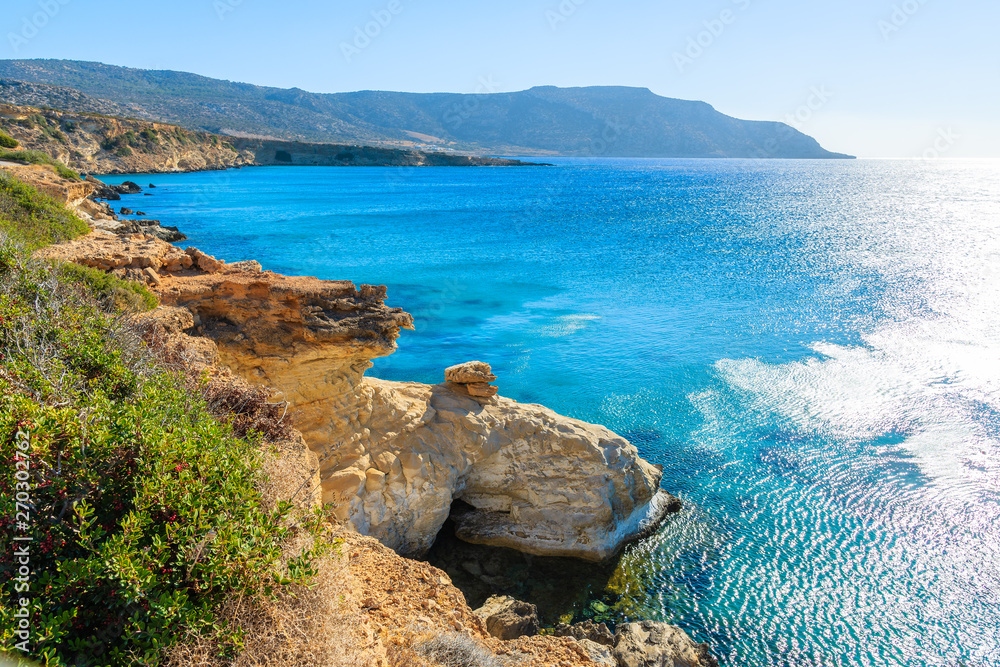 View of beautiful sun backlit sea coast with rocks at Ammopi beach, Karpathos island, Greece