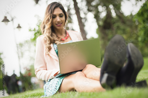 Young woman blogger freelancer enjoys in park with computer laptop
