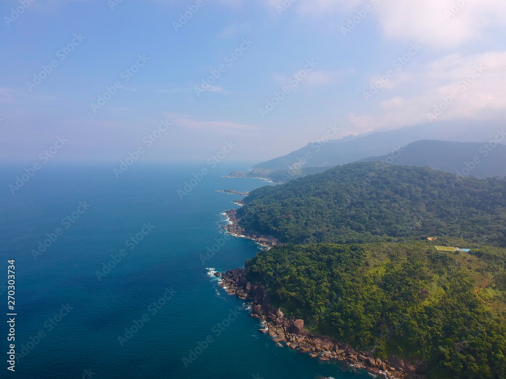 Aerial view of an amazing mountain coastline with blue & turquoise water in tropical country. Amazing top view of tropical forest next the sea. holiday destination island.