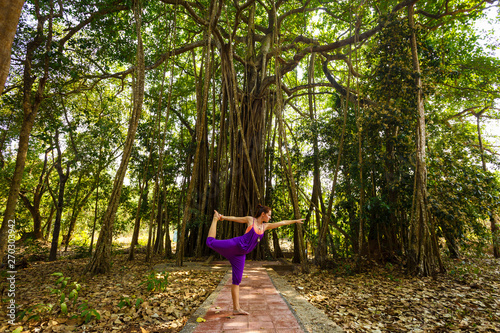 Woman makes yoga on a background jungle.