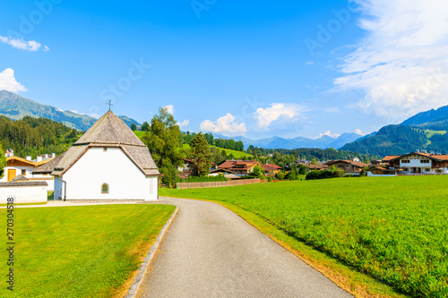 Road in countryside landscape near Kitzbuhel town and view of alpine houses, Tirol, Austria