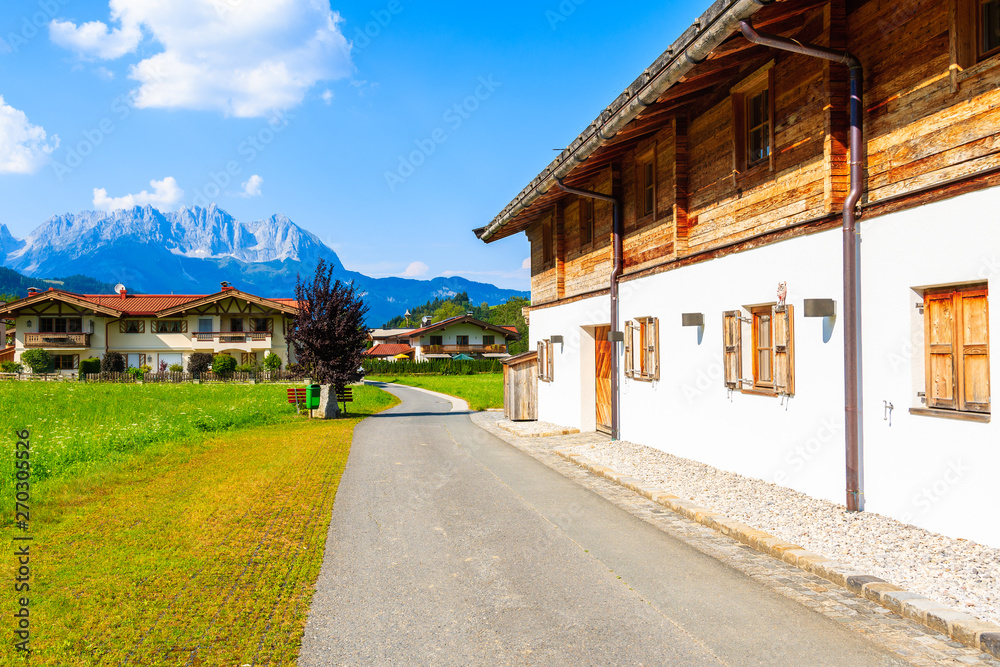 Road in countryside landscape near Kitzbuhel town and view of alpine houses, Tirol, Austria