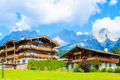 Traditional alpine houses in village of Going am Wilden Kaiser on beautiful sunny summer day with Alps mountains in background, Tirol, Austria