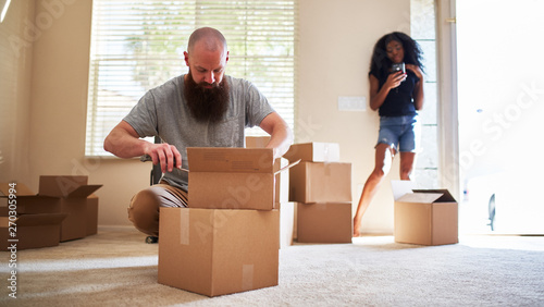 interracial couple moving into new house with boyfriend opening box © Joshua Resnick
