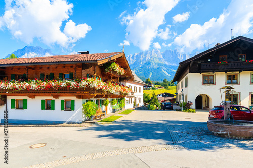 Traditional alpine houses on square in village of Going am Wilden Kaiser on beautiful sunny summer day with Alps mountains in background, Tirol, Austria