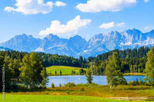 Green meadow against Alps mountains near Schwarzsee lake on sunny beautiful summer day near Kitzbuhel, Tyrol, Austria