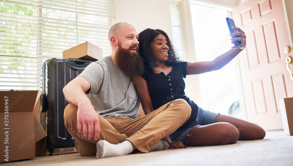 interracial couple taking selfie together while moving into new home