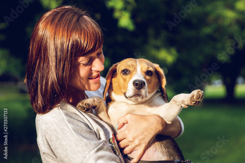 Girl holding a dog in her arms on the nature background at summer time. Lifestyle photo. © belart84