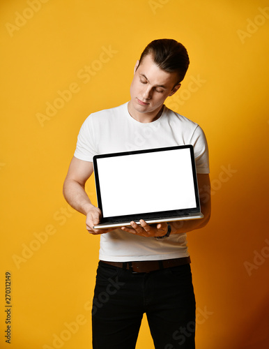 A handsome young man holding and showing the screen of a laptop