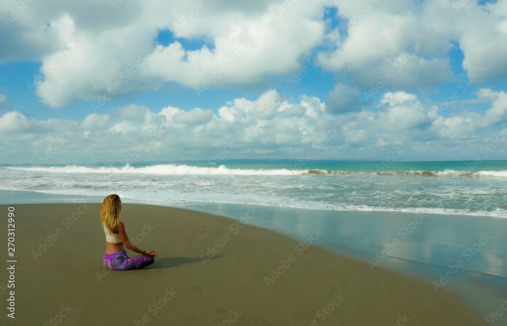 young happy and attractive blond girl doing yoga and concentration exercise outdoors at beautiful beach in relax and meditation practice sitting in lotus position young happy and attractive blond girl doing yoga and concentration exercise outdoors at beautiful beach in relax and meditation practice sitting in lotus position