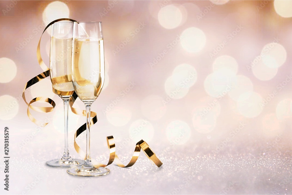 Glasses of champagne with curly ribbon on bright background Glasses of champagne with curly ribbon on bright background