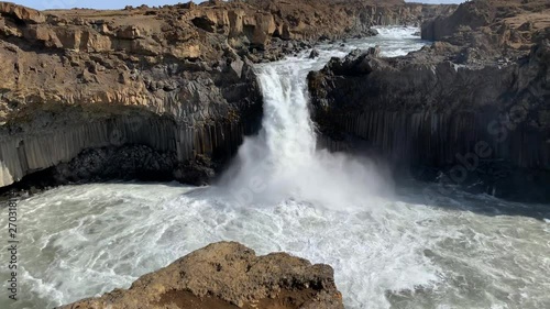 Basalt rocks next to majestic waterfall Aldeyjarfoss in the highlands of Iceland on a cold and windy day photo