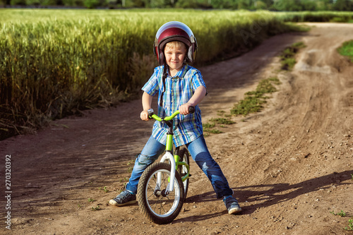 Fototapeta Naklejka Na Ścianę i Meble -  Portrait of a little boy on a Bicycle . The child wears a helmet . Summer walks in the fresh air