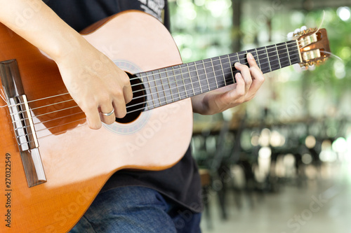 Asian man playing a classic guitar in blur background.