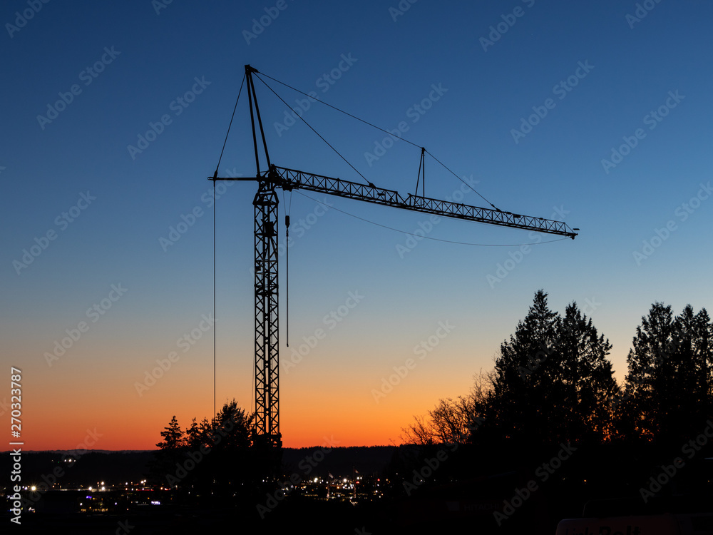 Tall construction crane silent in the sunset