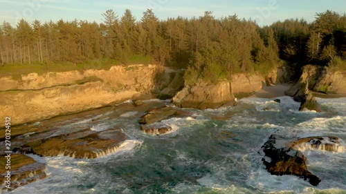 Drone flying backwards over the ocean, revealing dramatic cliffs of Yoakam Point near Coos Bay at  wild the Oregon Coast. photo