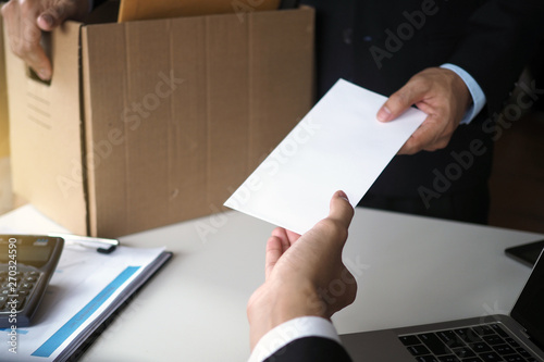 The business woman has a brown cardboard box next to her body and sends a letter of resignation to the executive. Include about resignation, job placement and vacancies.