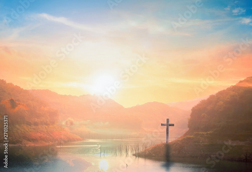 Surrender concept: Silhouette of crucifix cross on mountain at sunset time with holy and light background