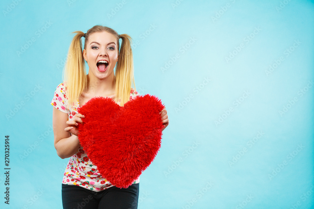 Happy woman holding heart shaped pillow Happy woman holding heart shaped pillow