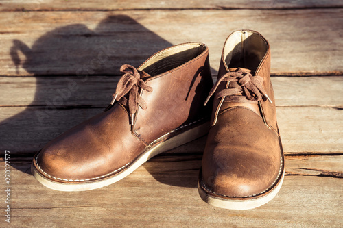 Brown stylish boots on wood background, retro color