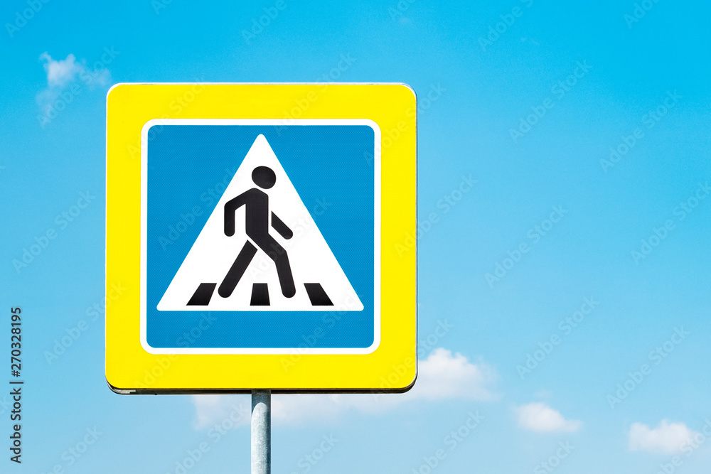Sign pedestrian crossing with a yellow frame against the blue sky on a sunny day. Copy space Sign pedestrian crossing with a yellow frame against the blue sky on a sunny day. Copy space