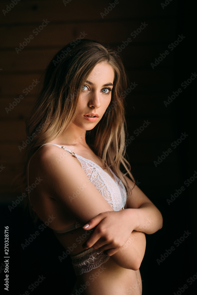 Fototapeta premium girl in lace underwear stands at the window looking straight.