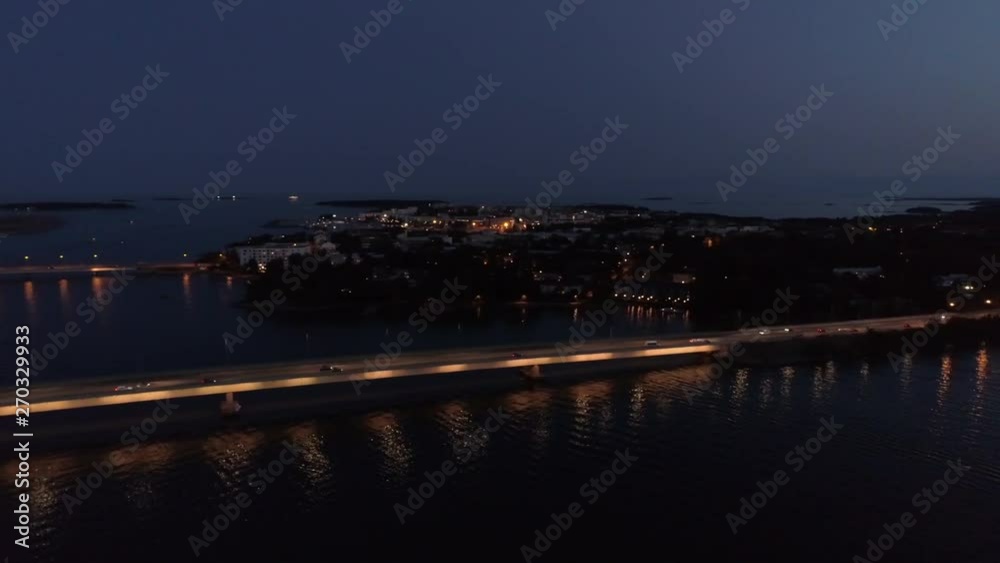 Aerial shot moving forward of a highway over the gulf at sea, cars driving away from the city by night Aerial shot moving forward of a highway over the gulf at sea, cars driving away from the city by night