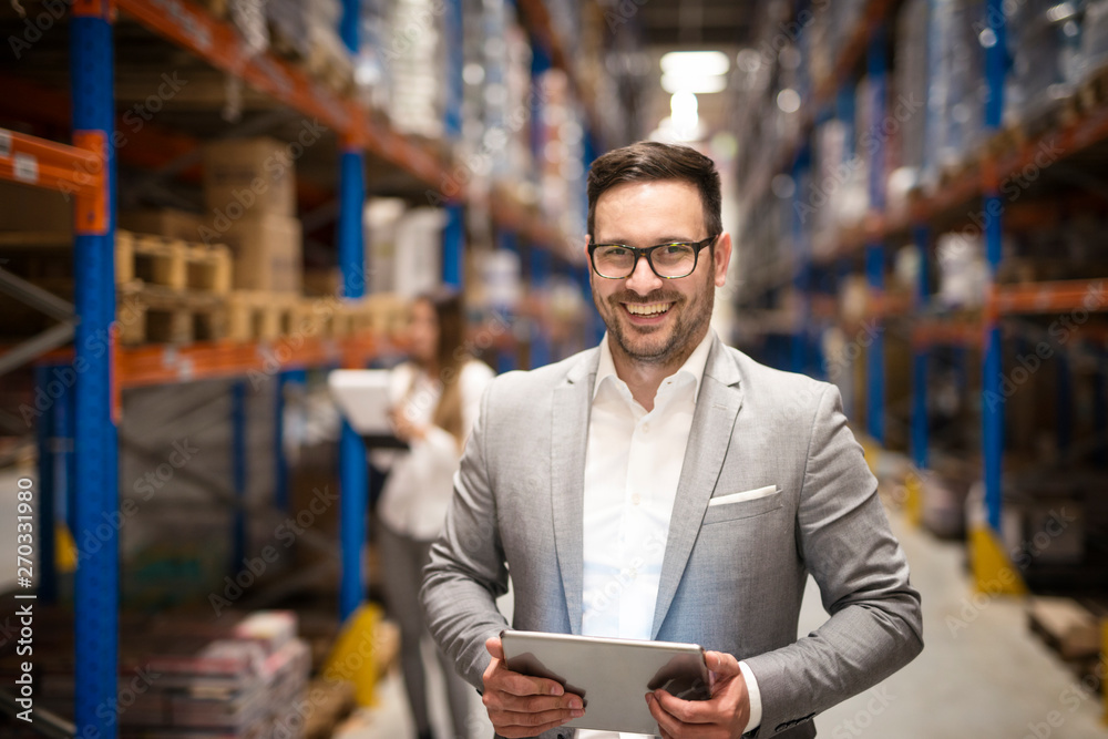 Portrait of successful middle aged caucasian manager businessman holding tablet computer in large warehouse organizing distribution. Business people. - obrazy, fototapety, plakaty 