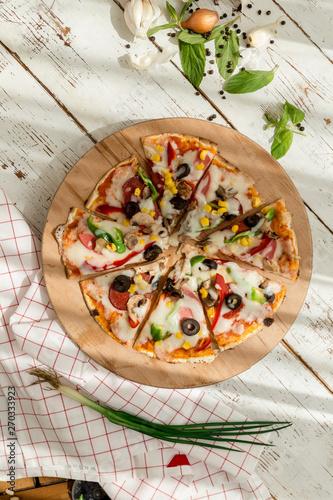 home made gourmet thin tortilla pizza on wooden plate and wood table gourmet food