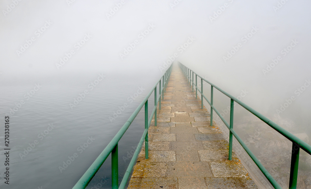 Long pier with green handrails going into nowhere     